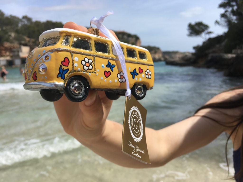 Žlutý hippie minibus. Skleněná ozdoba jako dárek na cestách. Pláž na Mallorce.